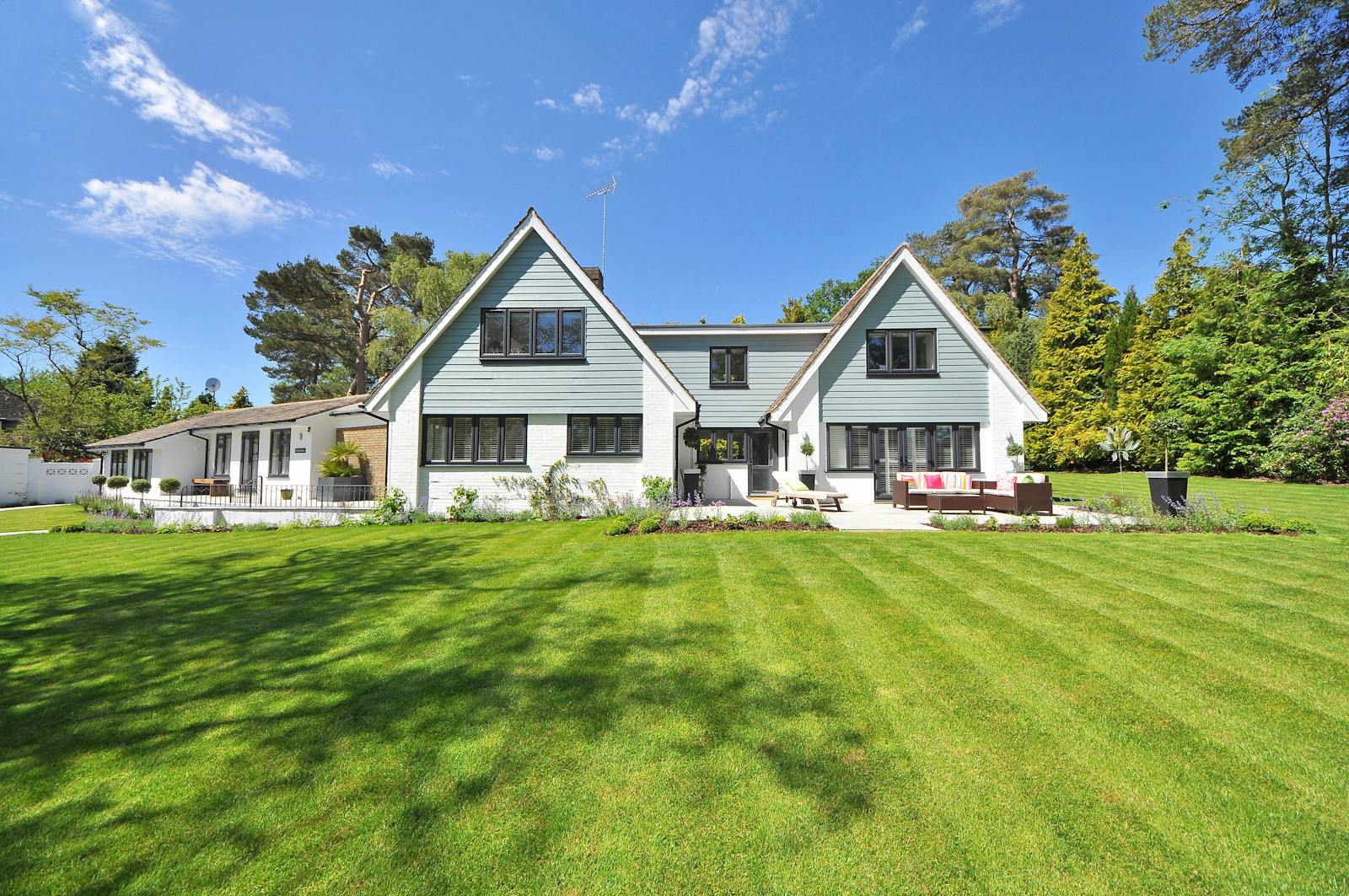 White-painted Texas home with a healthy lawn and well-kept shade trees at the curb.